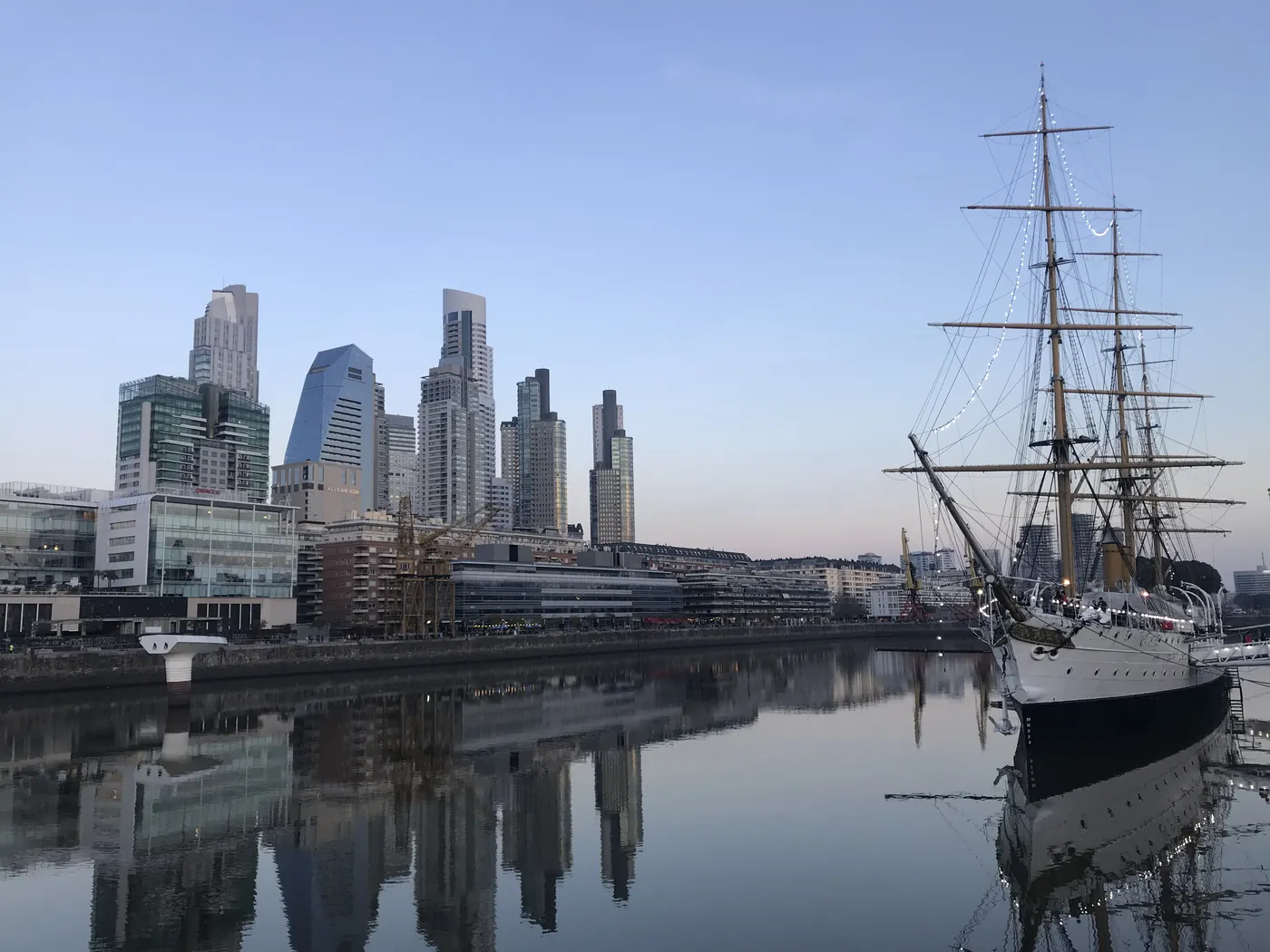 Buenos Aires al atardecer. Torres reflejadas en el agua y un velero amarrado a la derecha