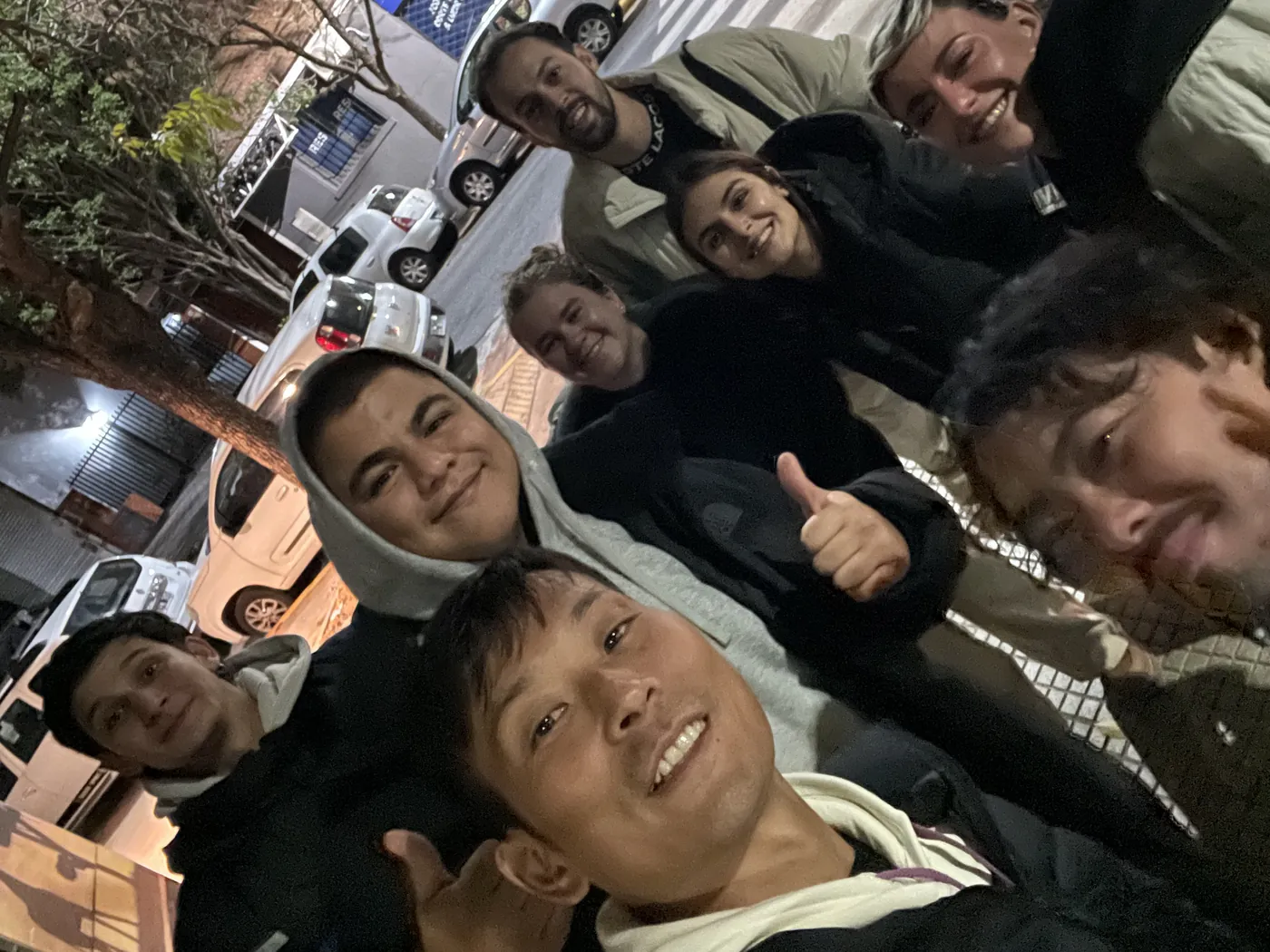 夜の街角。8人ほどが顔を寄せ合って笑っている集合写真