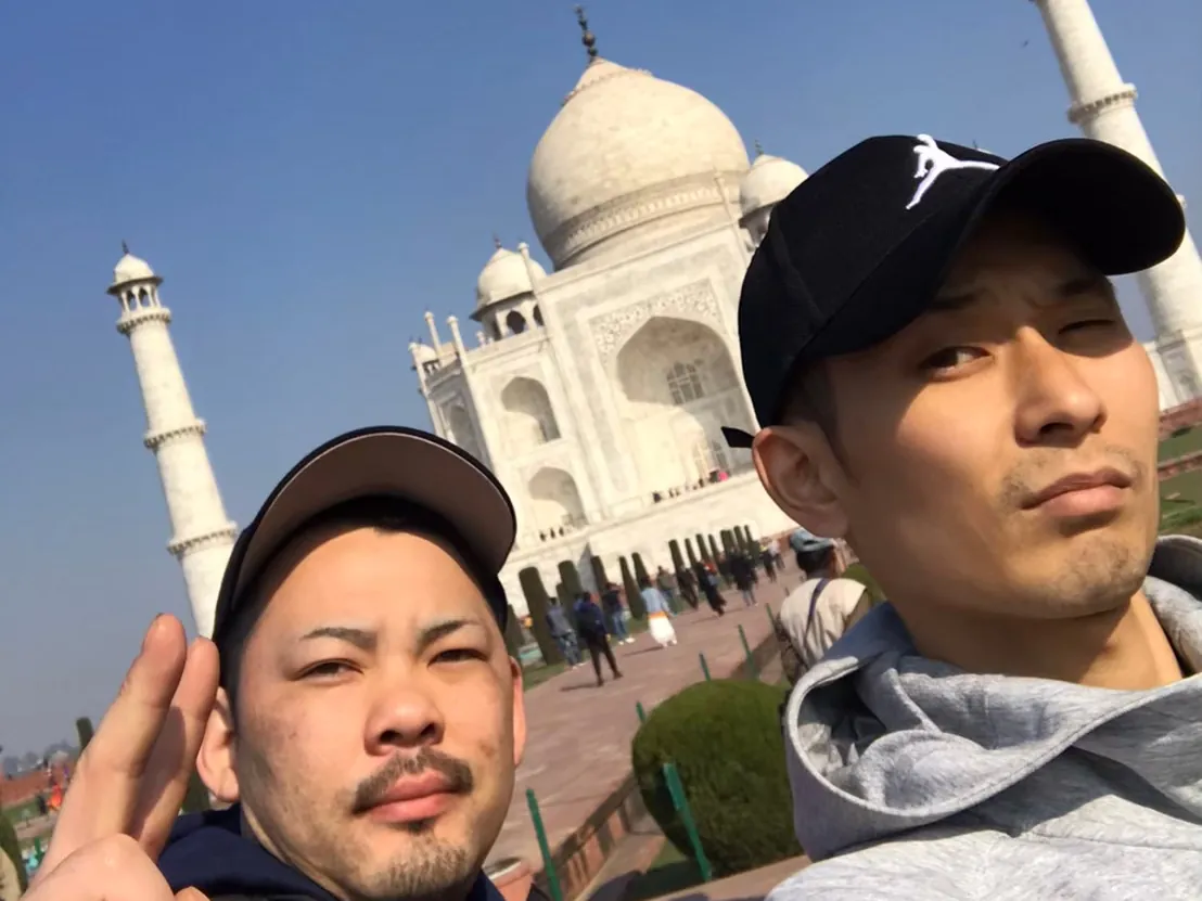 タージ・マハルを背にした二人の旅行者。どちらも帽子をかぶっている