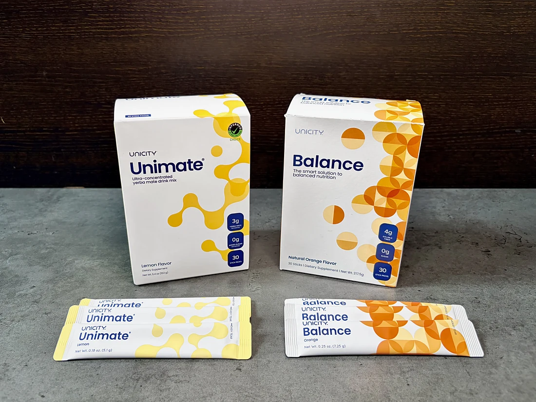 Unimate和Balance的盒裝產品立在深色木牆前的混凝土檯面上，前方排列着兩者的條裝包